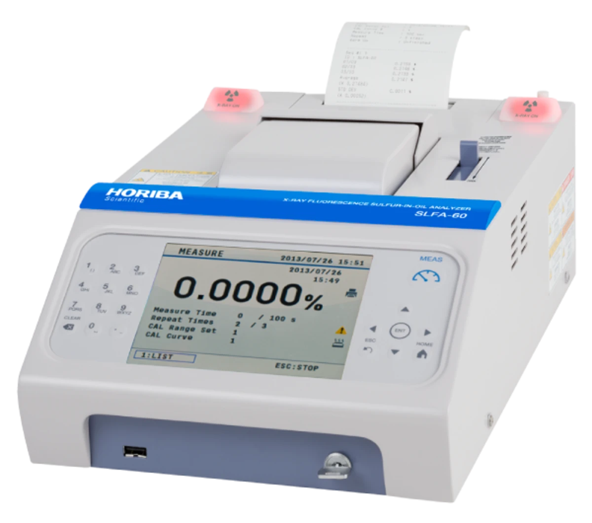A scientific instrument with a large display screen showing measurement data, buttons, and a blue label with "HORIBA" text. It features a paper printout coming from the top, with red indicator lights on each side. The device is labeled "SLFA-60".